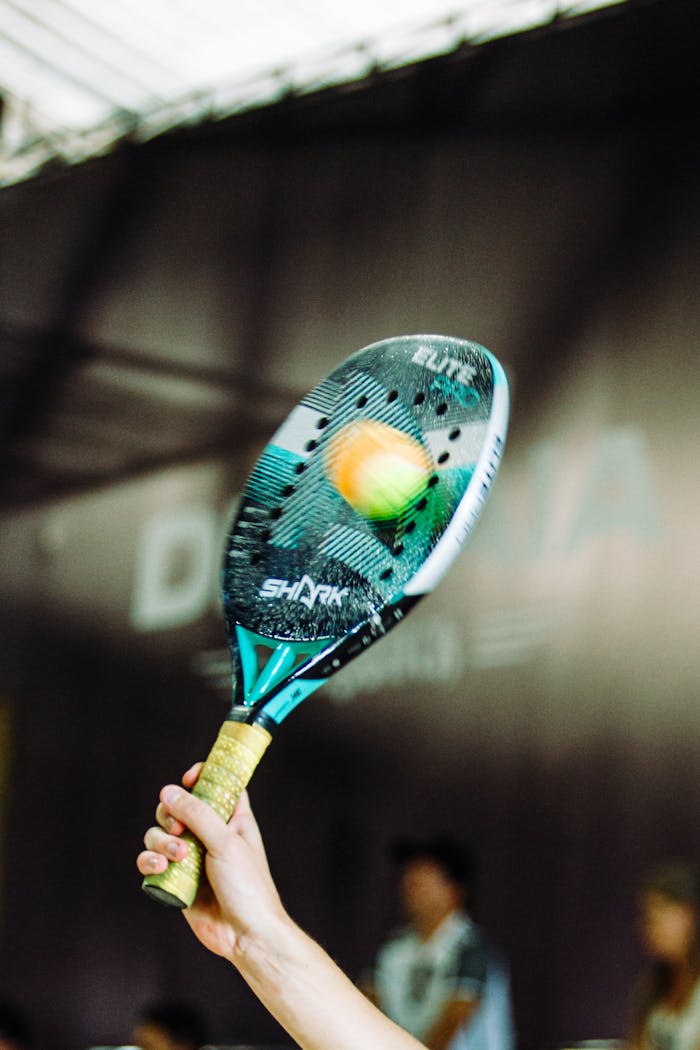 Action-packed padel racquet hitting ball indoors during intense match.
